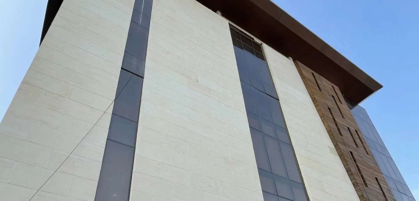 Commercial facade combining sandstone-look panels, glass strips, and wood-look cladding